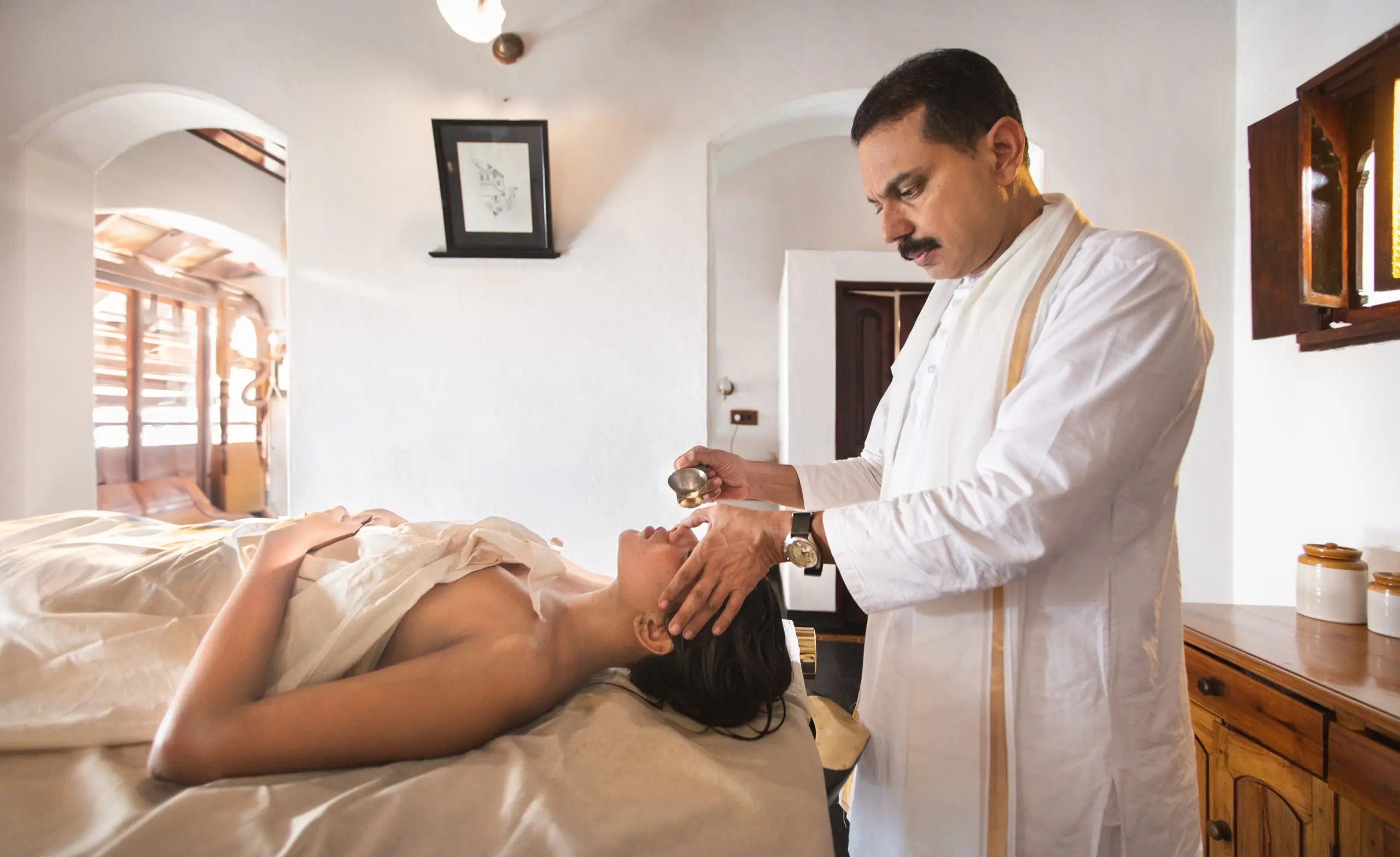 A small vessel of oil brought to the guest's brow, in a whitewashed room.